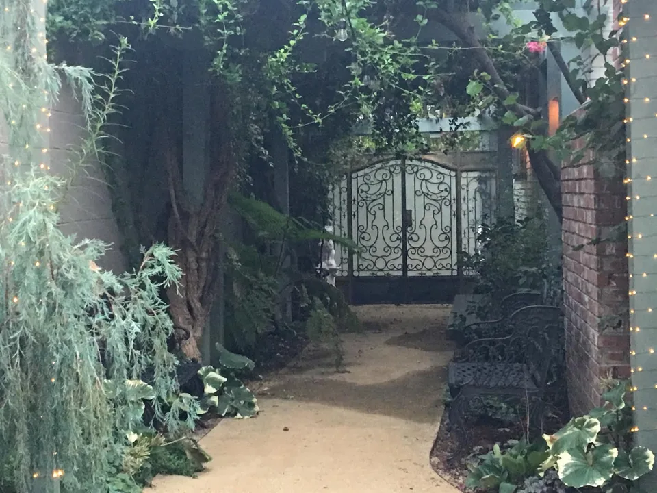Ornate iron gates at the end of a planted garden corridor.
